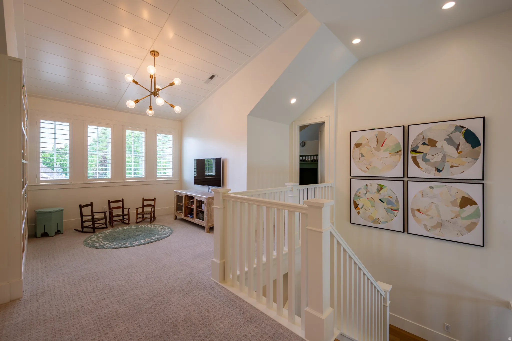 Upper-level landing featuring vaulted ceilings with shiplap detailing, recessed lighting, and a contemporary brass chandelier