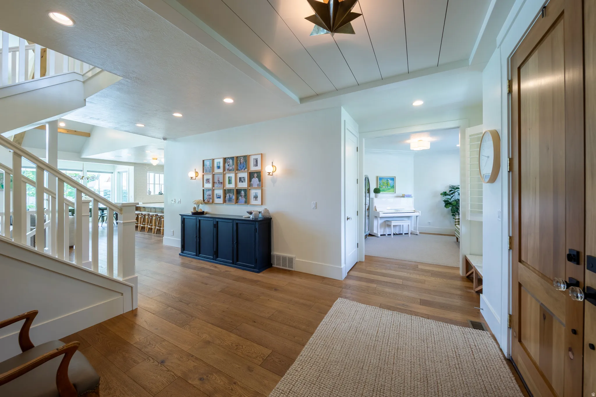 Inviting entryway featuring wood-finish flooring, a white spindle staircase, recessed lighting, and a shiplap ceiling