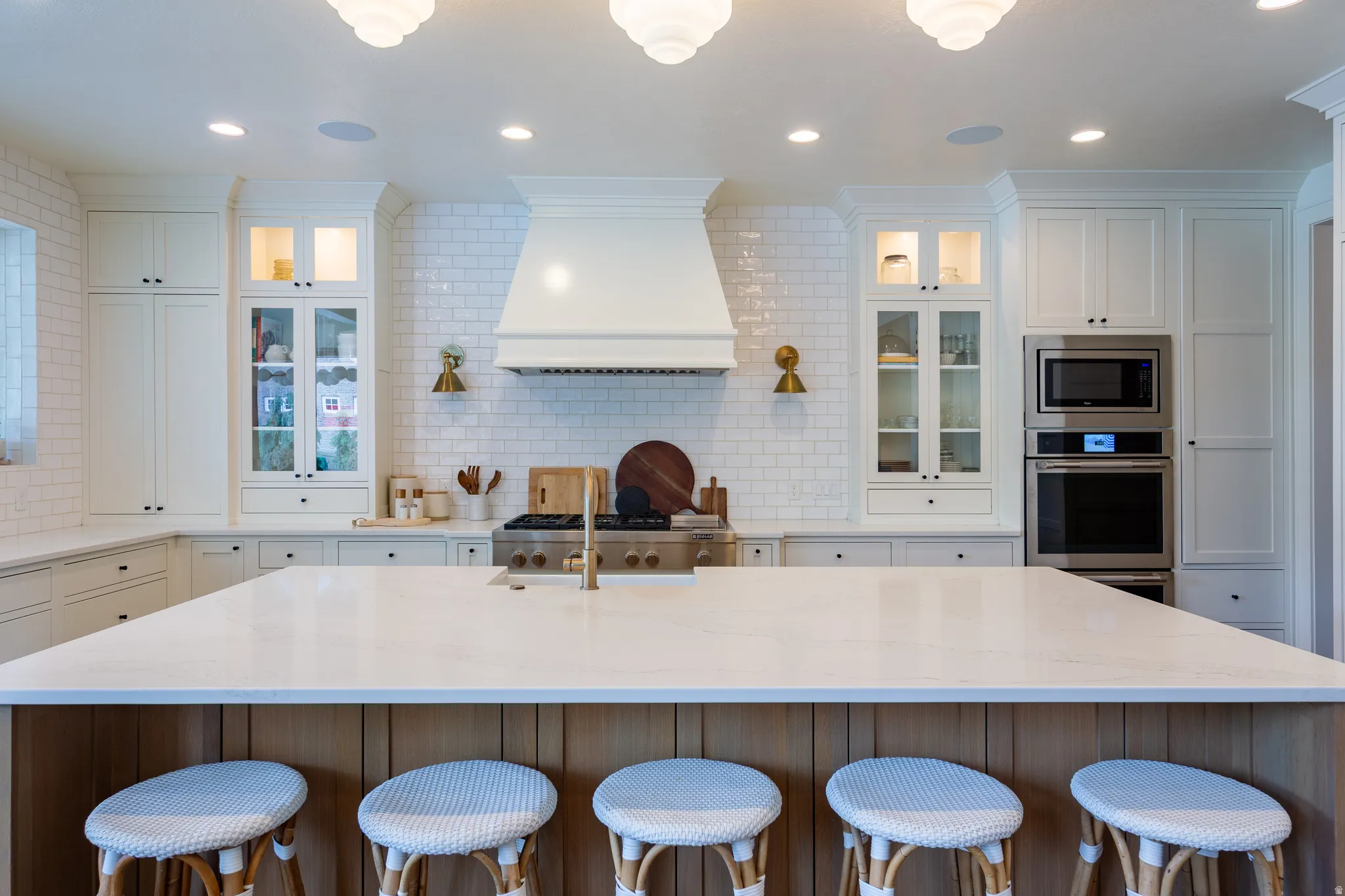 Spacious kitchen featuring a large central island with a light-toned countertop, white shaker-style cabinetry, and a white subway tile backsplash