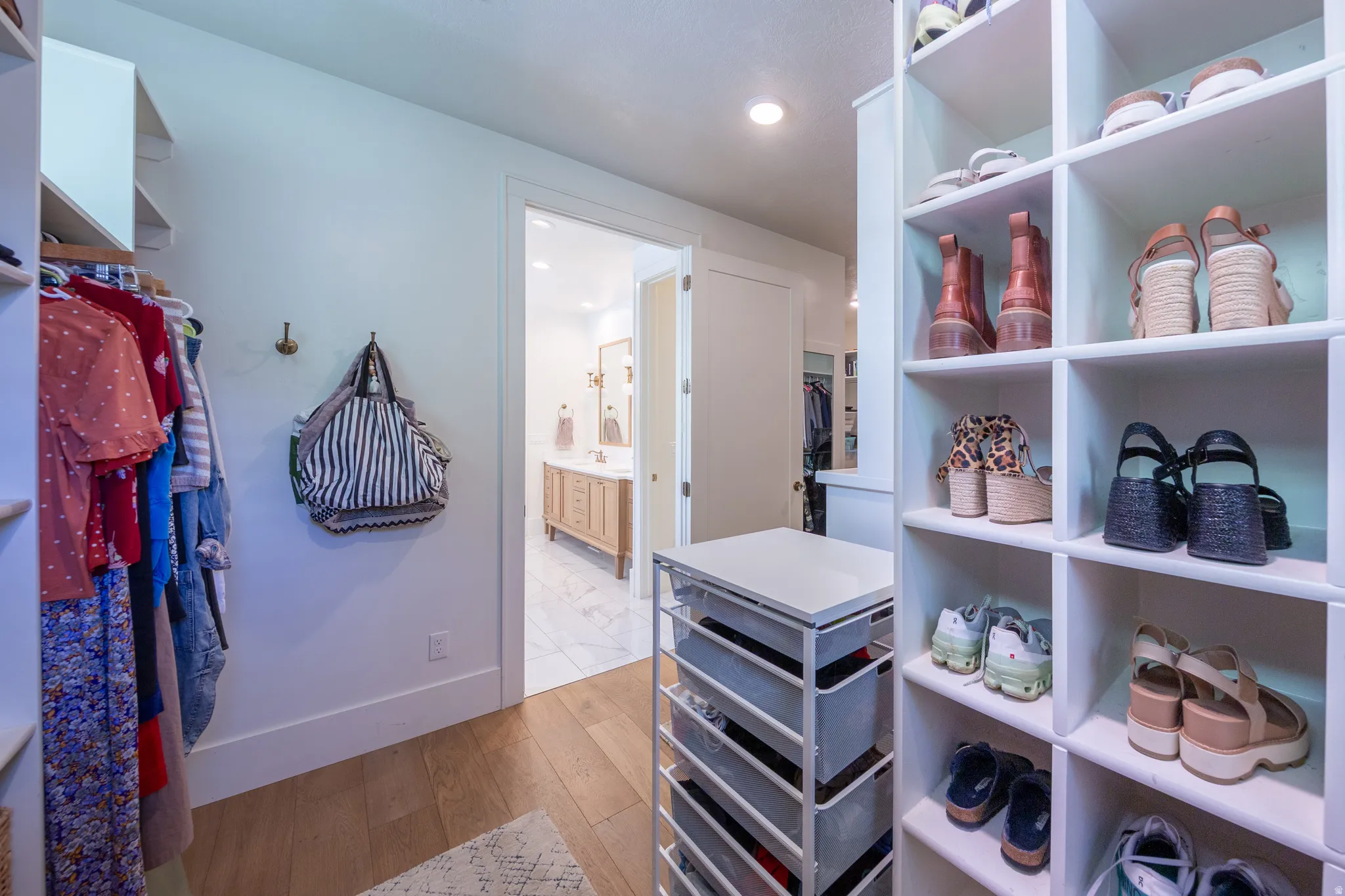Walk-in closet featuring wood-finish flooring, built-in shelving, and a built-in dresser with a white countertop