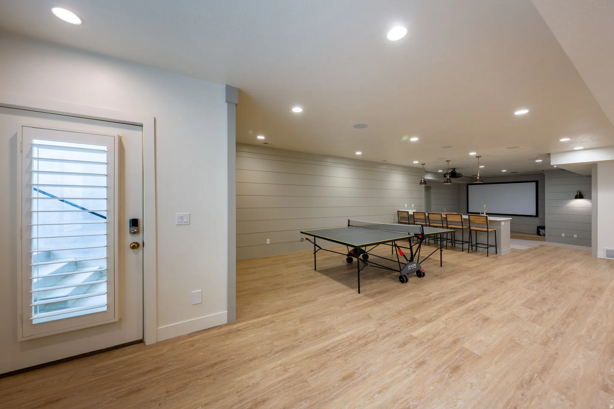 Spacious recreation area featuring wood-finish flooring, recessed lighting, and shiplap accent walls