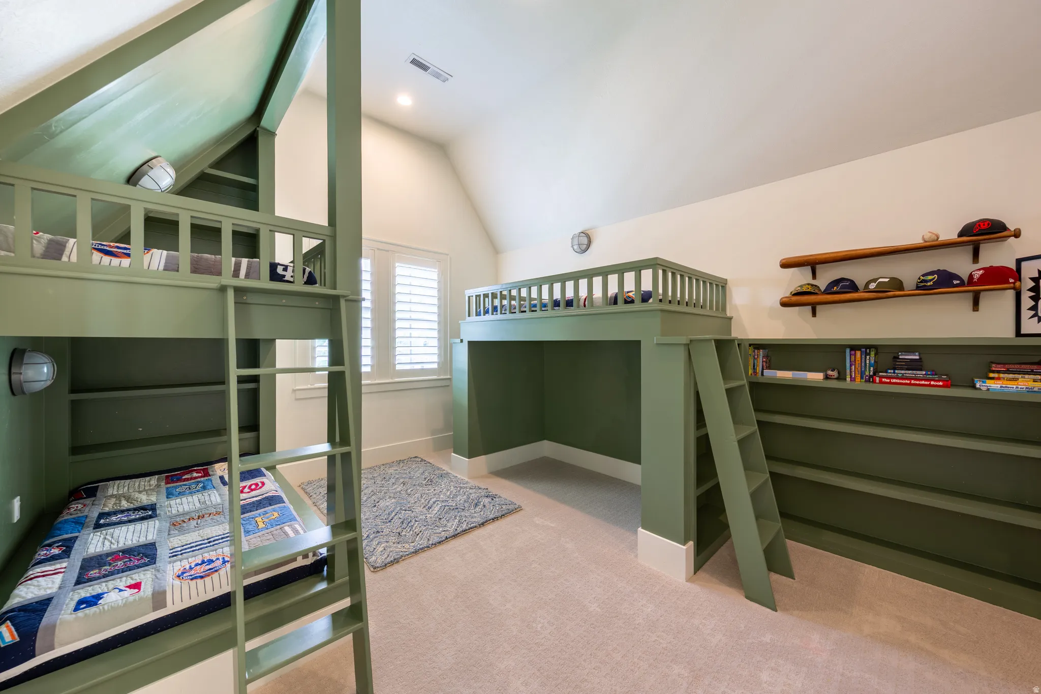 Built-in bunk beds with integrated shelving and ladders, accompanied by a loft bed structure featuring an open area below