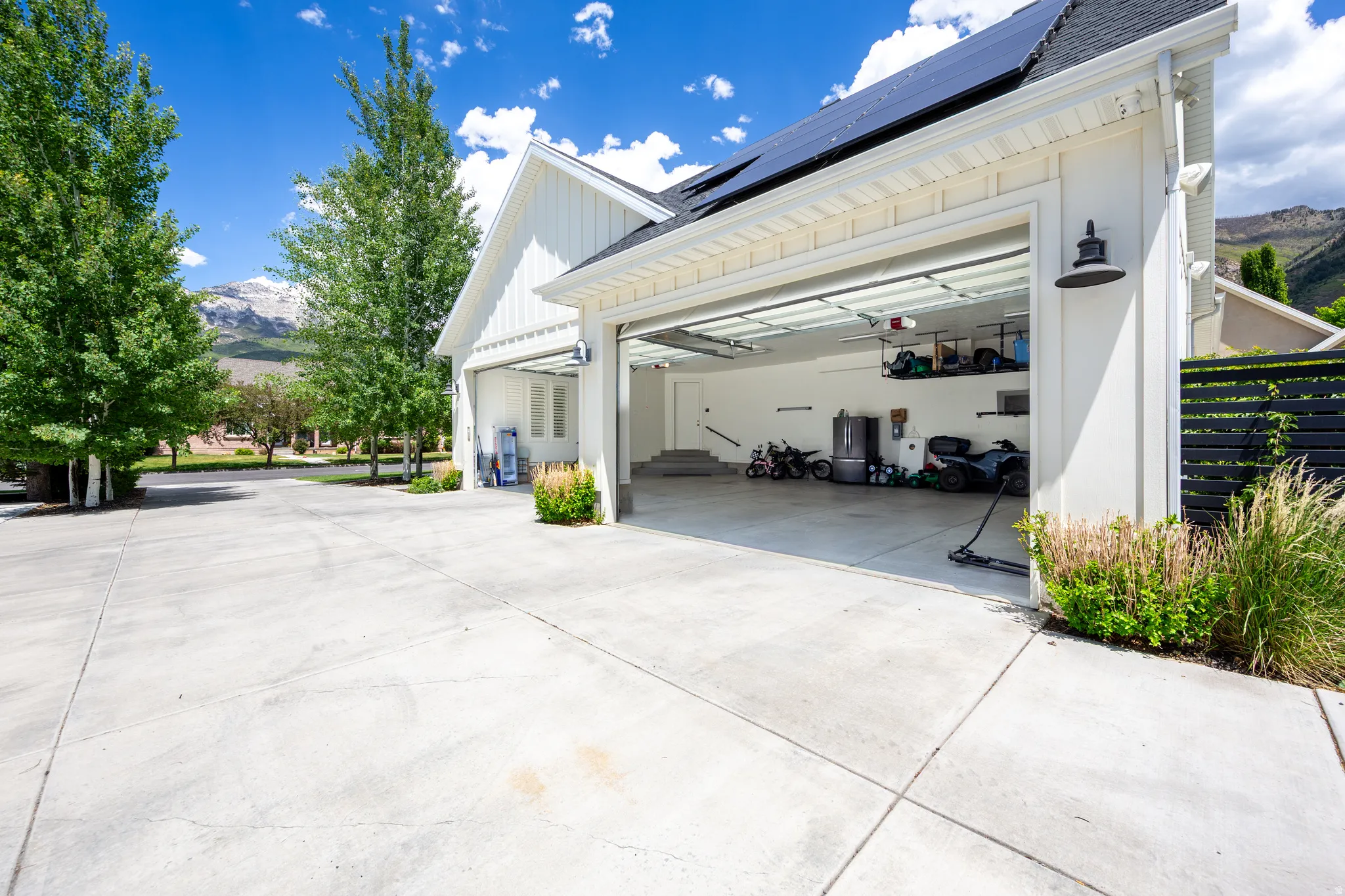 Three-car garage with modern overhead doors, board and batten siding, and solar panels