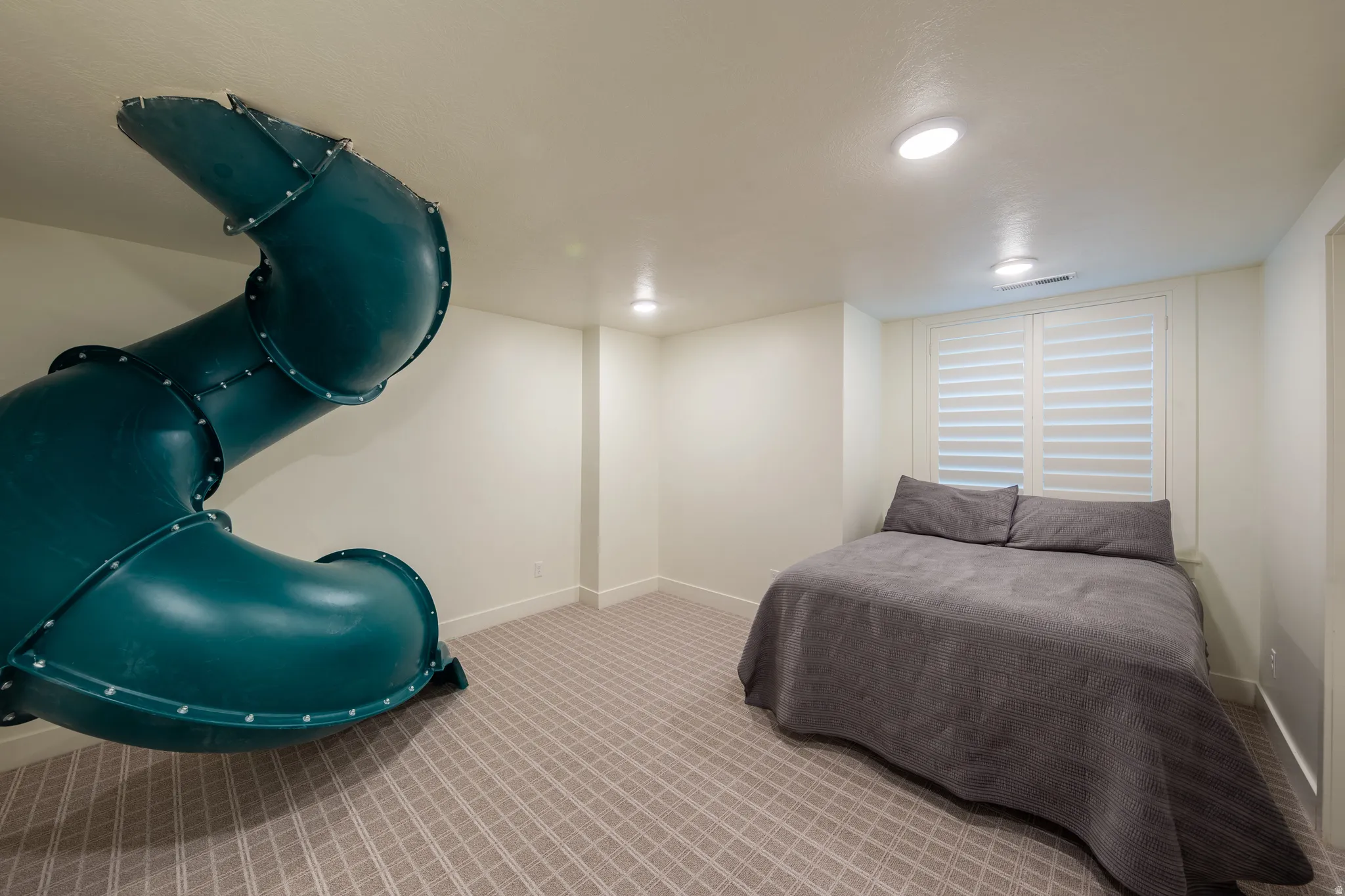 Interior room featuring a built-in spiral slide, recessed ceiling lighting, textured wall-to-wall carpeting, and plantation shutters