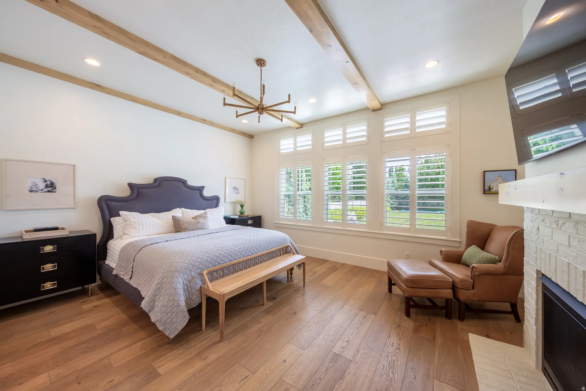 Spacious room featuring wood-finish flooring, exposed ceiling beams, recessed lighting, and a linear chandelier