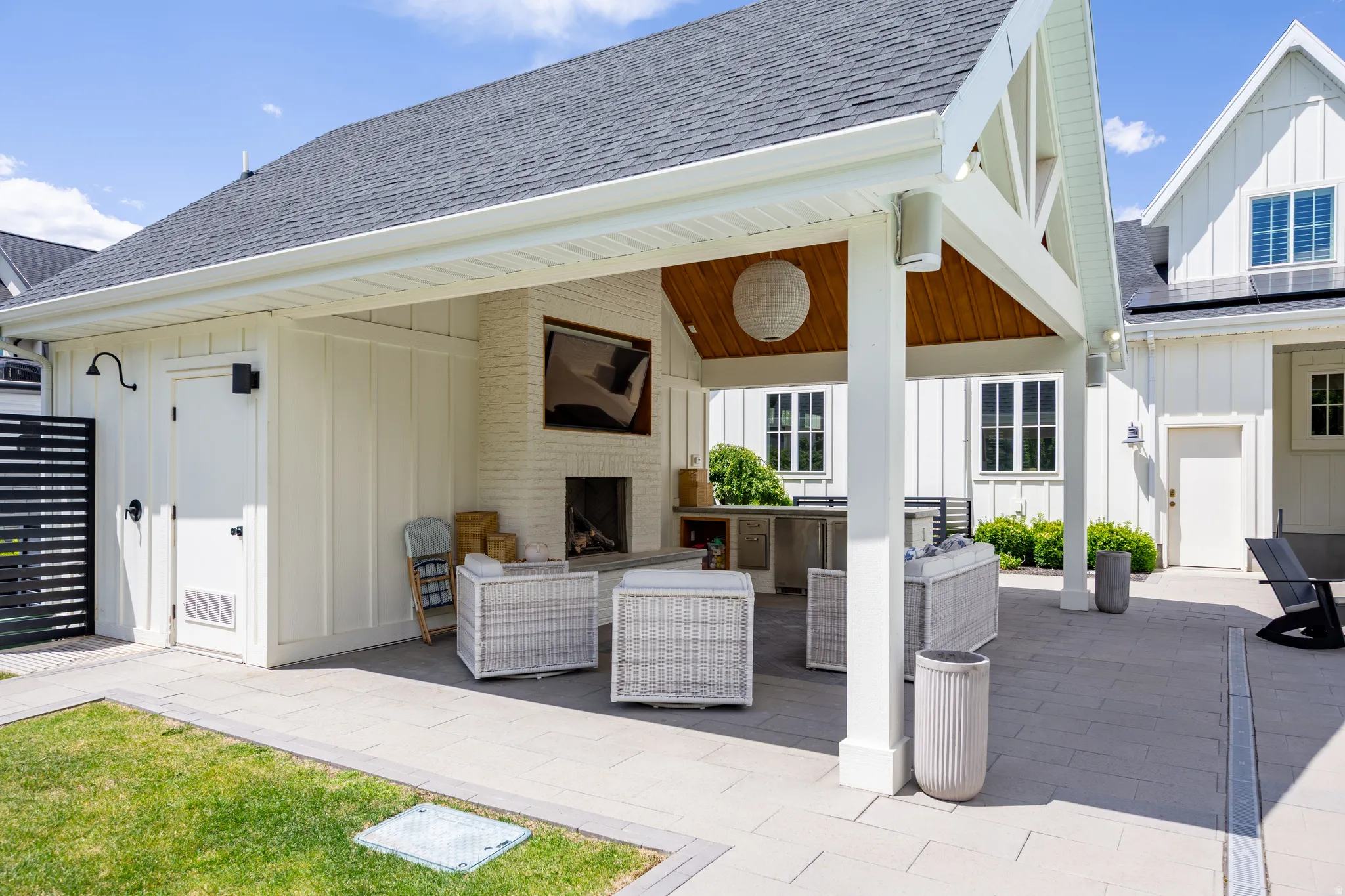 Expansive outdoor living area featuring a covered patio, built-in fireplace, exposed wood ceiling, and paver stone flooring