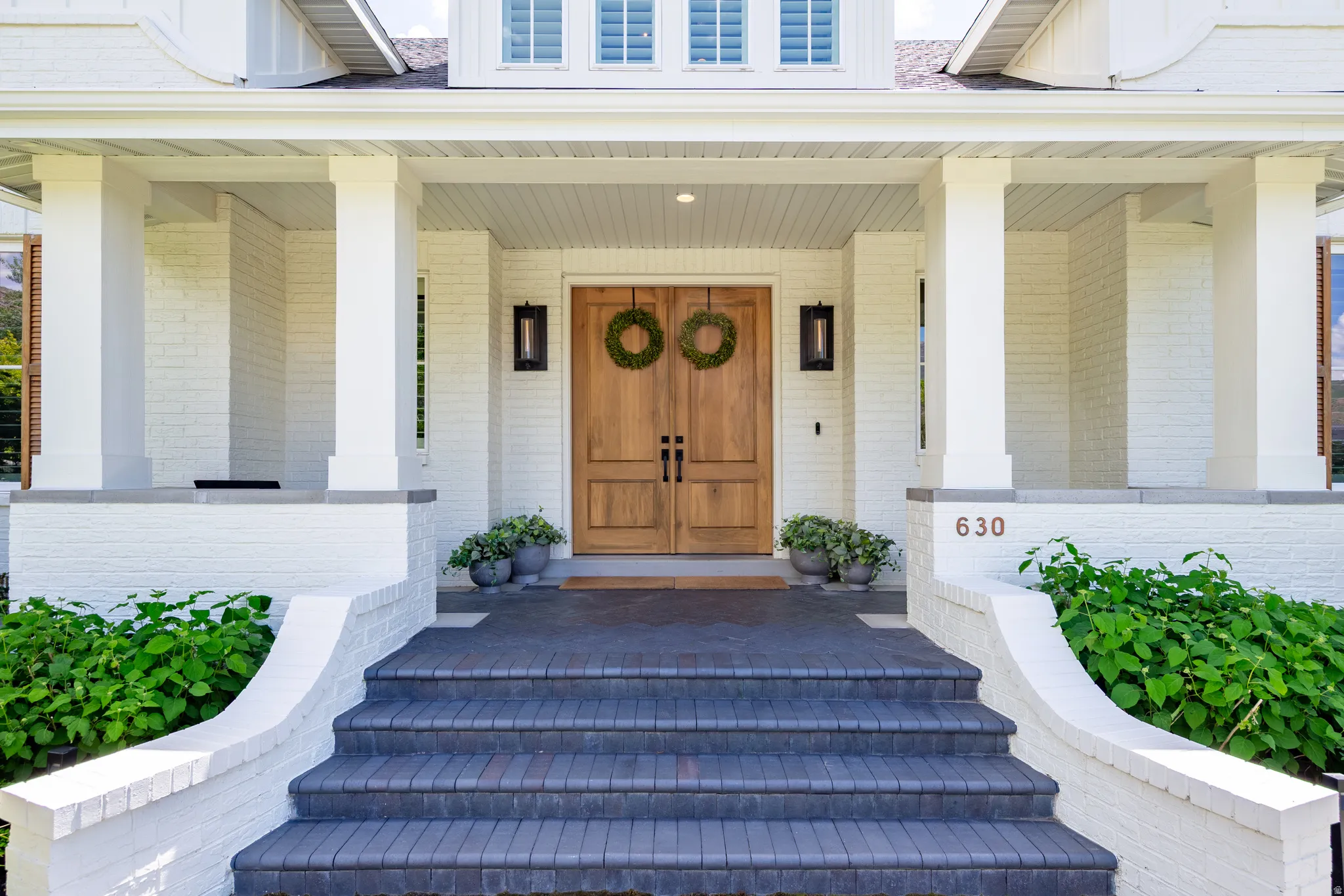 Inviting entry with double wood doors and painted brick facade