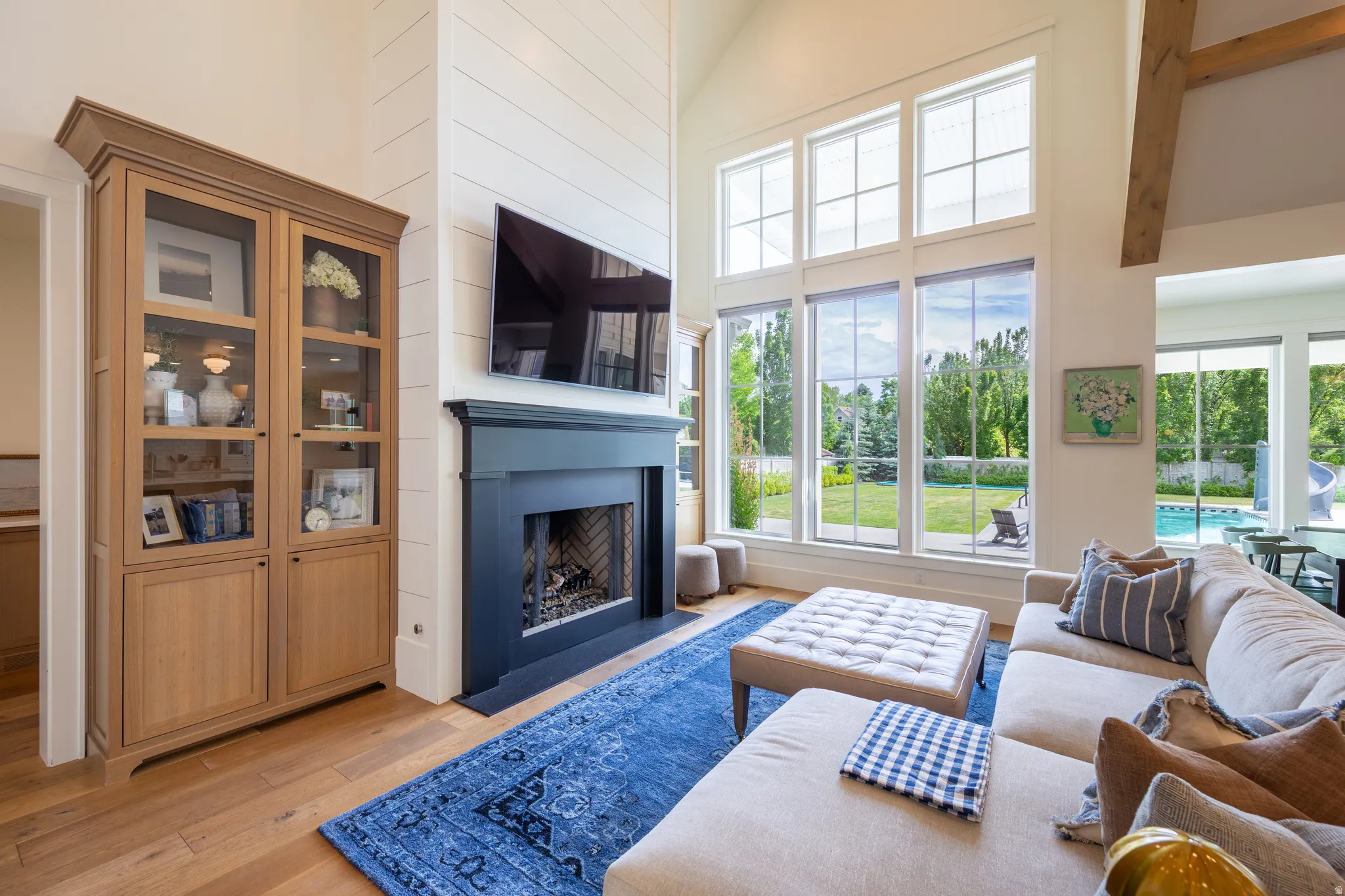 Vaulted living space featuring wood-finish flooring, a fireplace with a dark mantel, and expansive windows