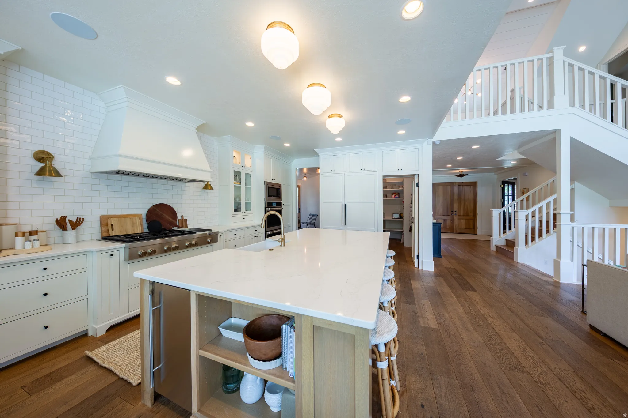 Gourmet kitchen featuring an oversized island with countertop seating, a professional-grade range with a custom range hood, white subway tile backsplash, and extensive cabinetry