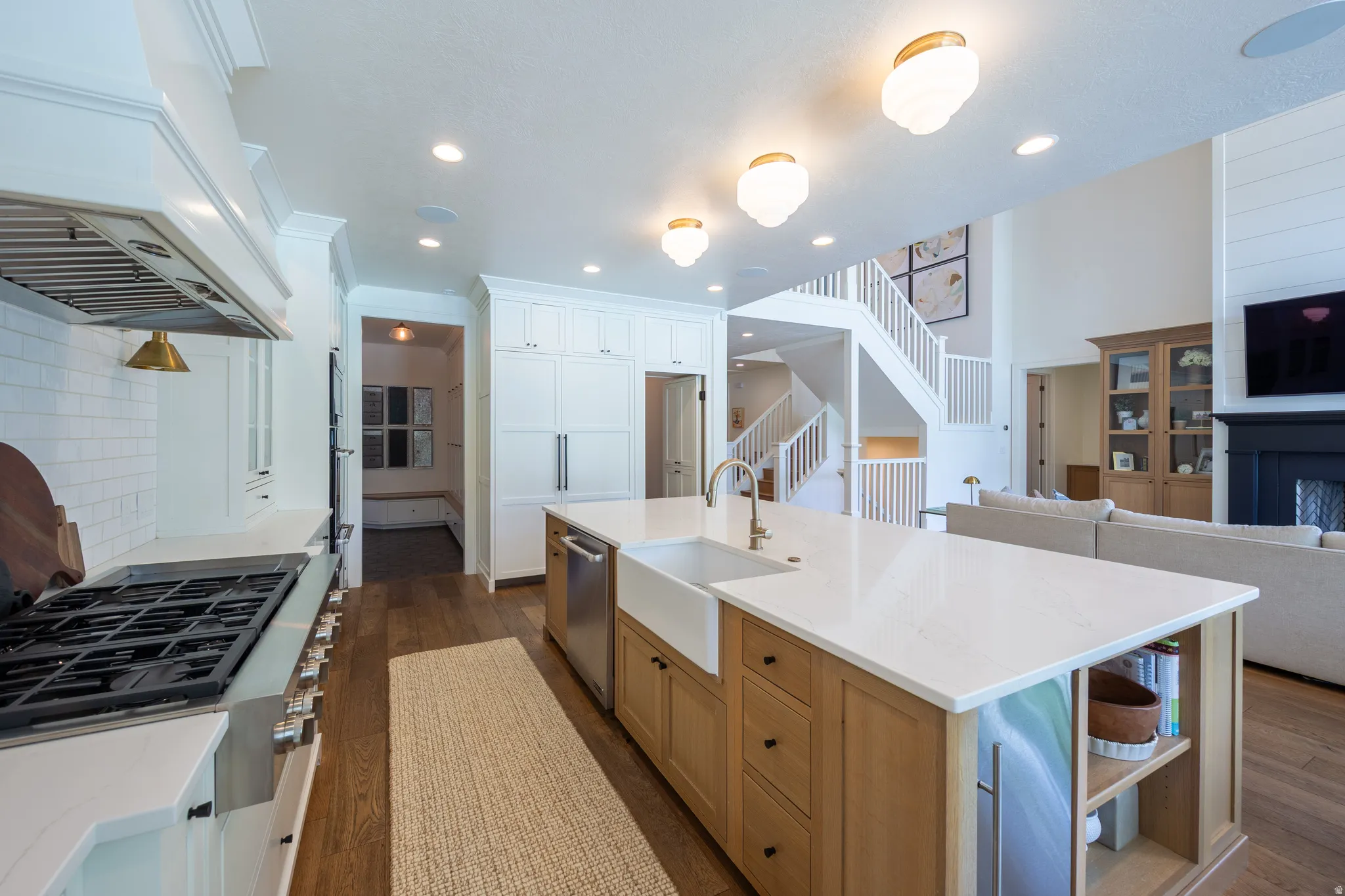 Spacious kitchen featuring an expansive central island with a farmhouse sink, white countertops, and wood-finish cabinetry
