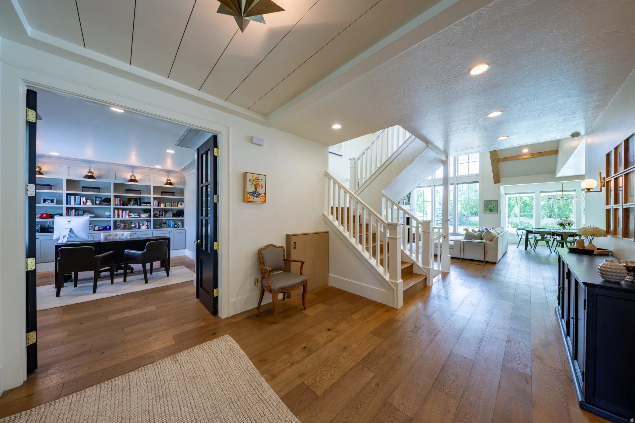 Wide plank wood-finish flooring extends through the open concept living areas, featuring a prominent staircase with white balusters