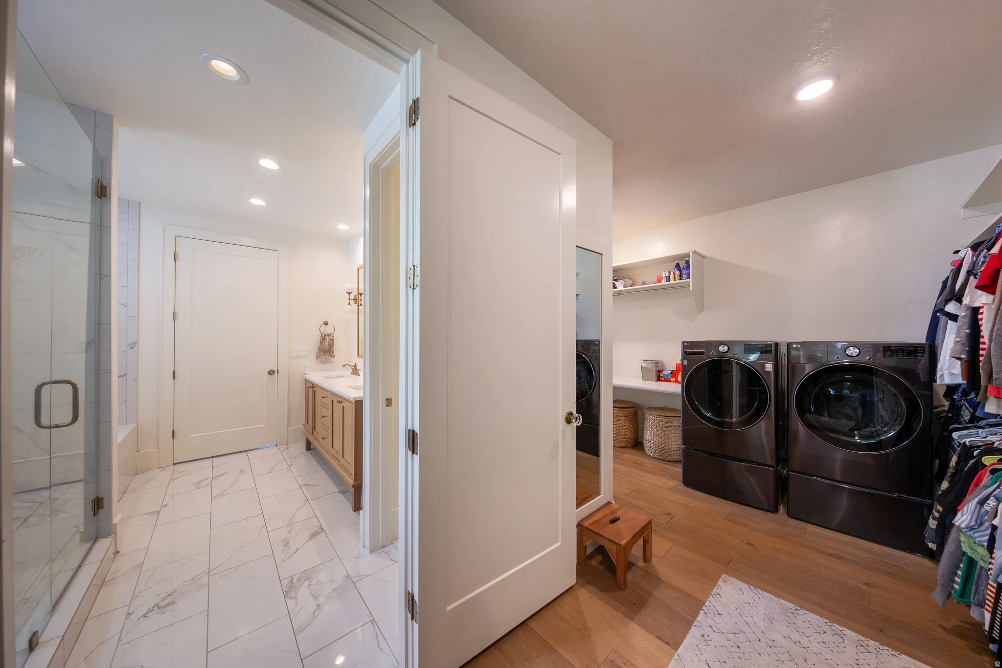 Integrated laundry and wardrobe area featuring wood-finish flooring, a built-in shelving unit, and recessed lighting