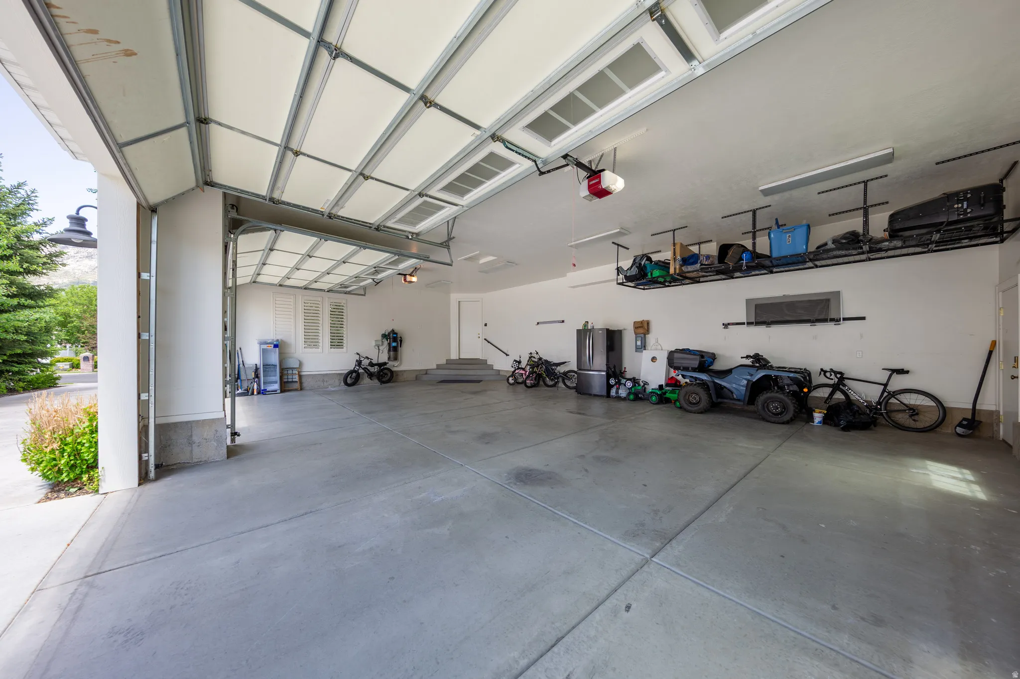 Spacious garage featuring concrete flooring, an automatic overhead door, and two wall-mounted storage racks