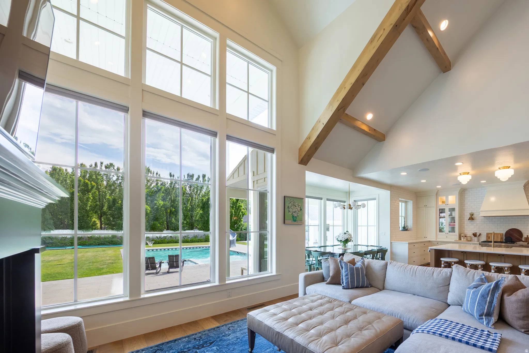 The great room features a vaulted ceiling with exposed wood beams, a custom fireplace mantel, and wood-finish flooring
