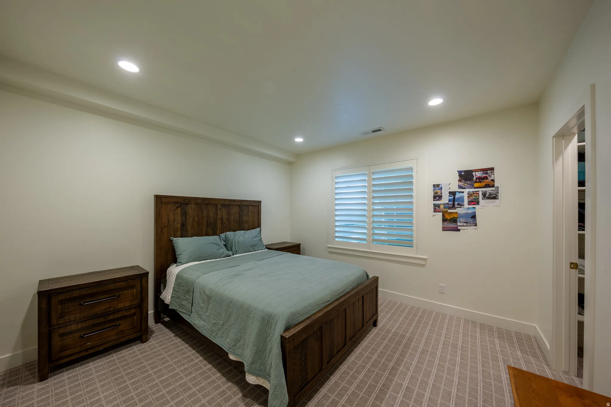 Recessed ceiling lighting illuminates a room featuring light-toned walls and patterned carpeting