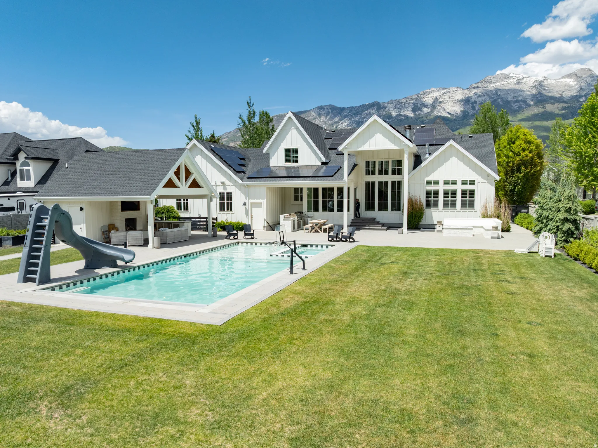 Expansive backyard featuring a rectangular swimming pool with integrated slide, a generous lawn area, and a paved patio
