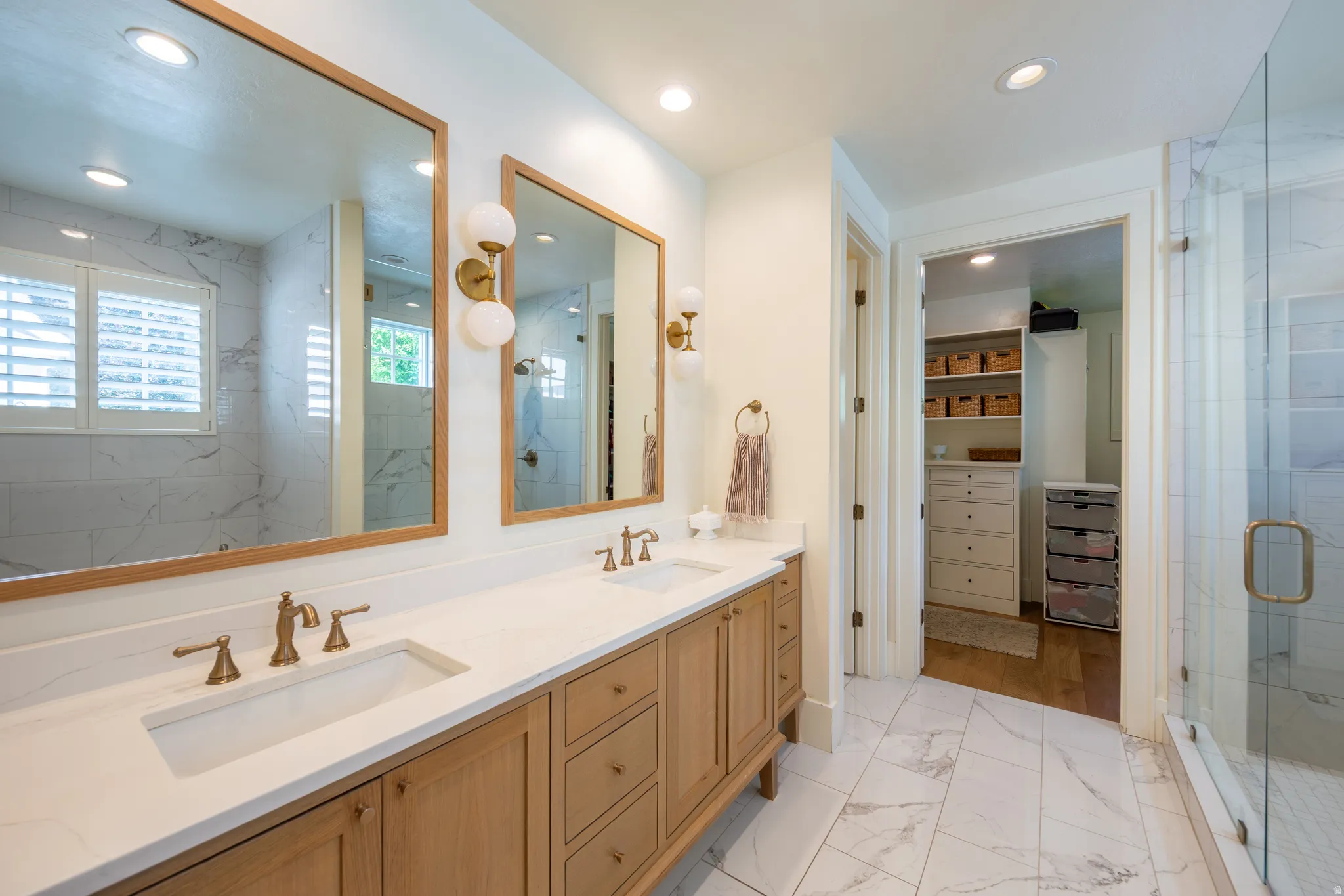 Bathroom featuring a dual vanity with light wood cabinetry, white countertops, and bronze-finish fixtures