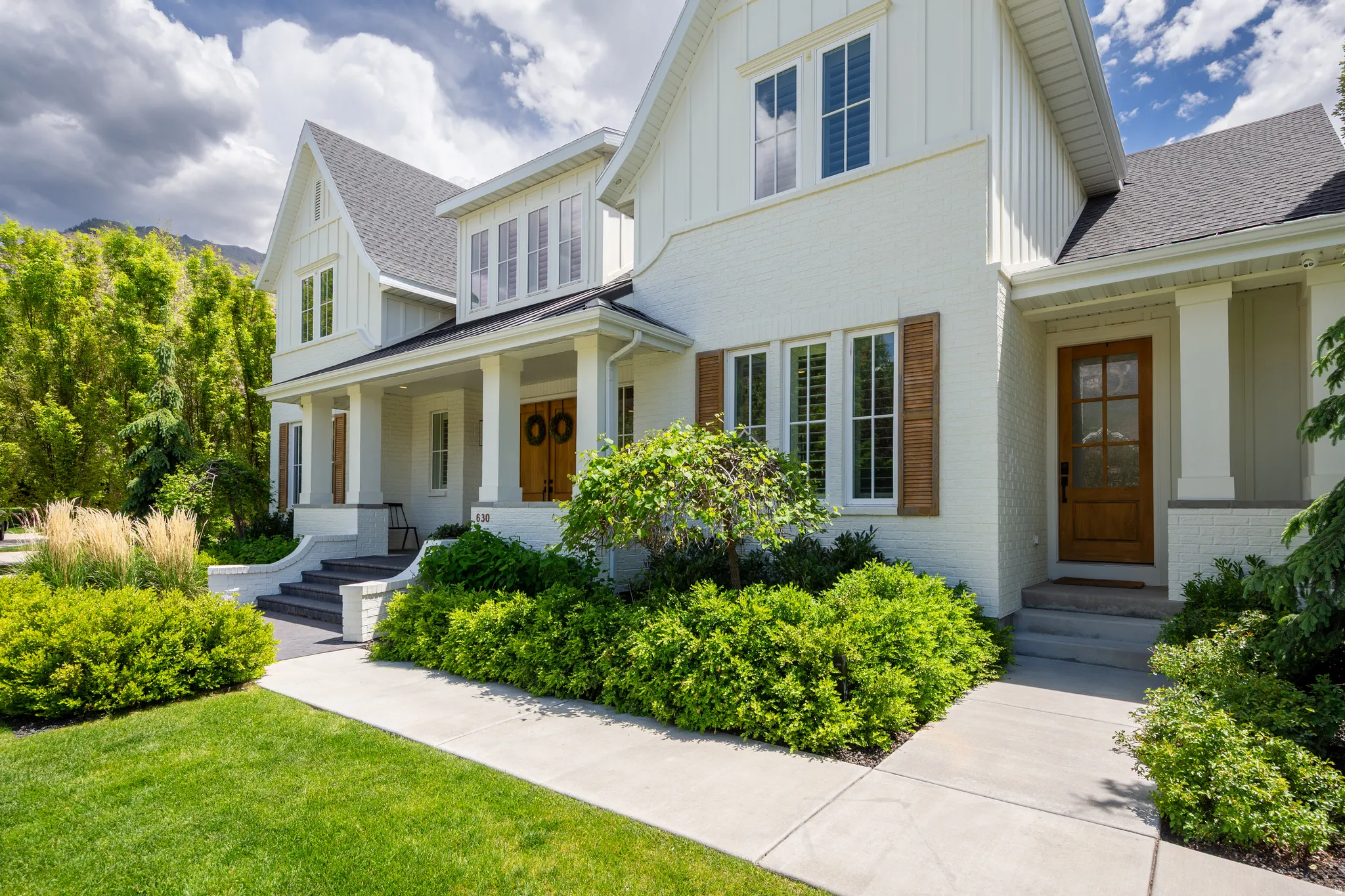 White brick and board-and-batten exterior with dark shingle roofing