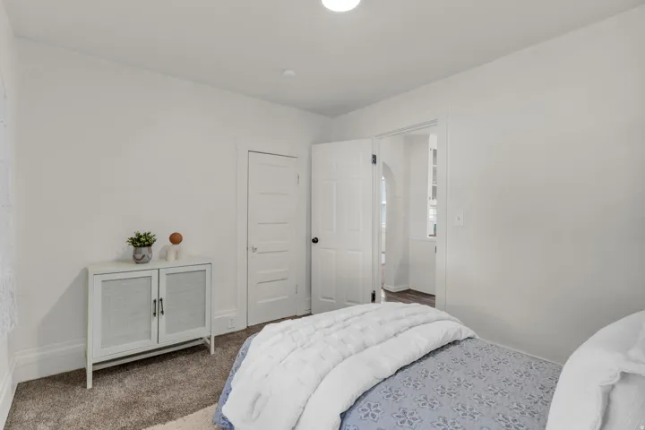 Carpeted room with a white door and an arched doorway revealing a separate space