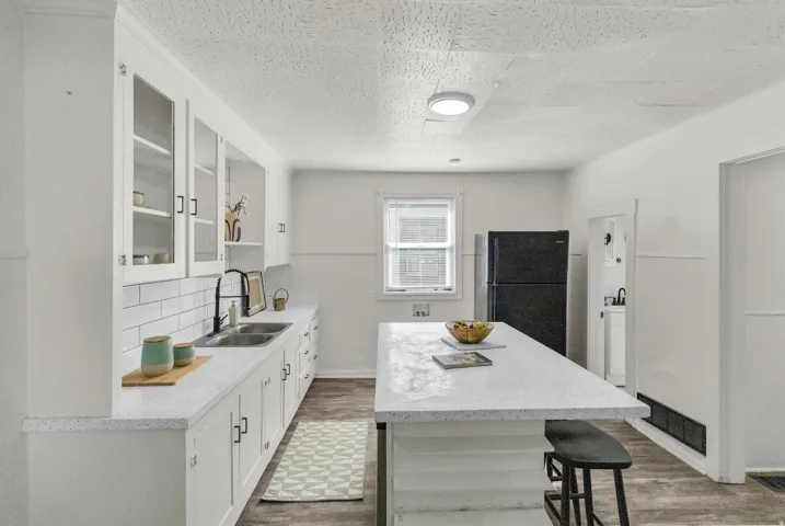 Kitchen with white cabinetry, glass-front upper cabinets, and a subway tile backsplash