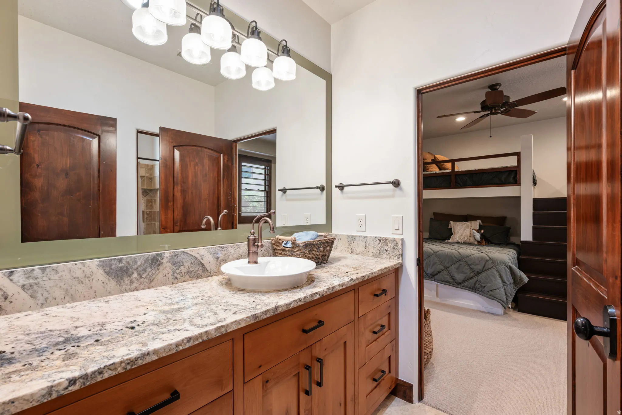 Bathroom vanity featuring a stone countertop, a white vessel sink, and a bronze-finish faucet
