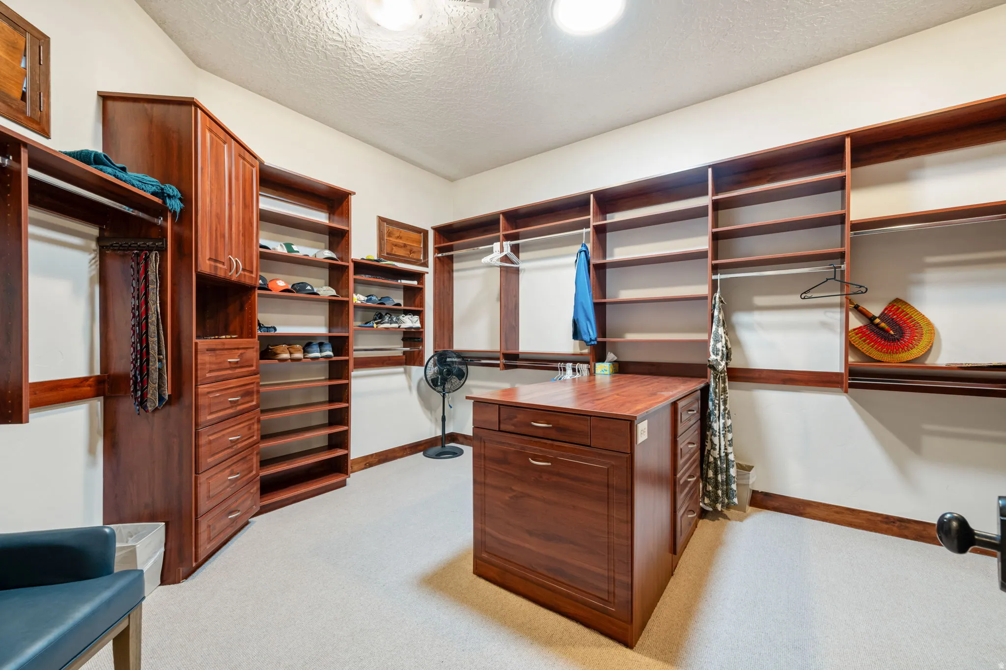 Spacious custom closet featuring extensive built-in shelving, multiple hanging rods, and a central island with integrated drawers