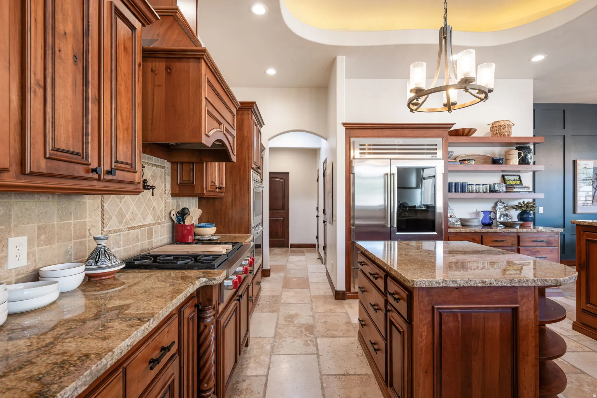 Gourmet kitchen featuring custom wood cabinetry, granite countertops, a large center island, built-in stainless steel appliances, and tile flooring