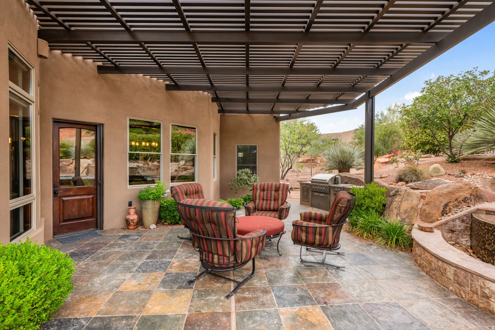 Spacious outdoor patio featuring multi-toned flagstone paving, an integrated outdoor grill station, and a decorative water feature