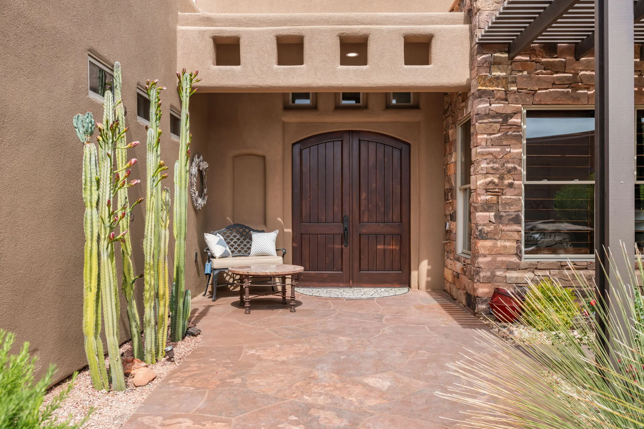 Arched double entry doors set within a stucco facade with decorative square cutouts