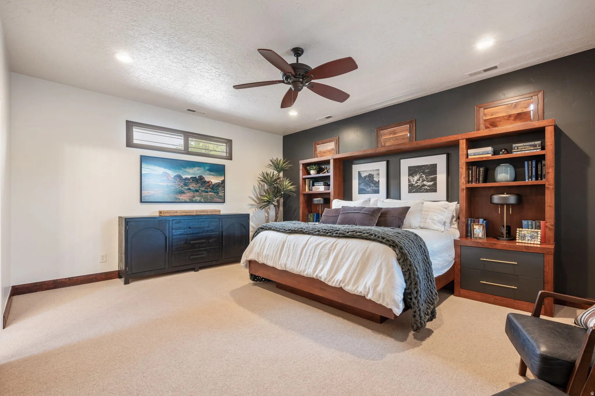 Built-in wood-finish shelving and cabinetry flank the bed, complemented by a ceiling fan with integrated lighting