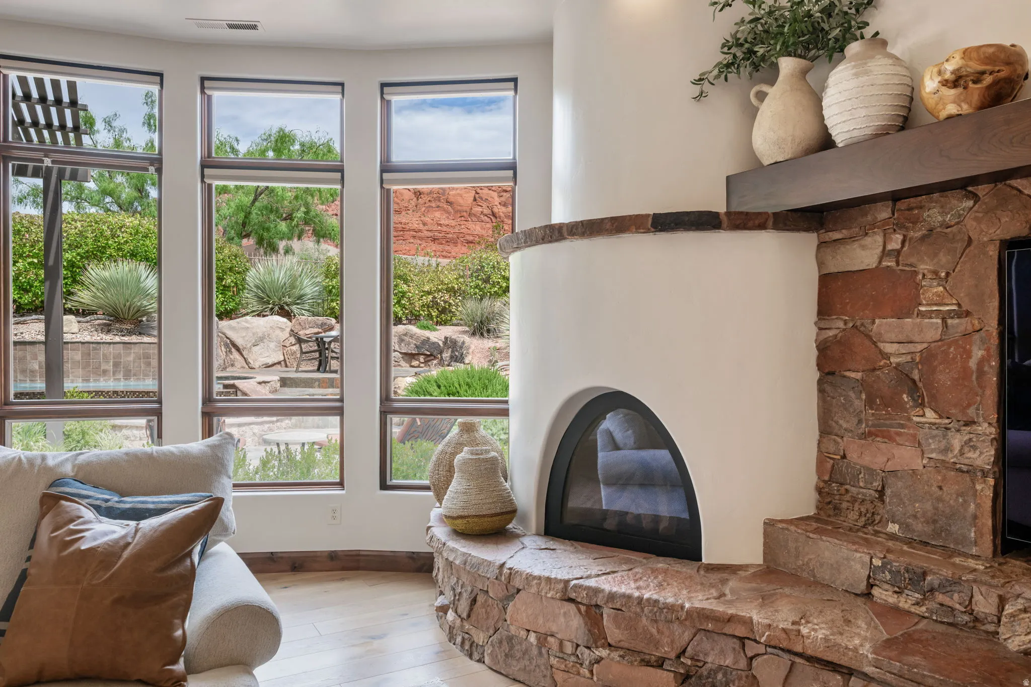 Curved stucco fireplace with stone surround and hearth, featuring a wood mantel