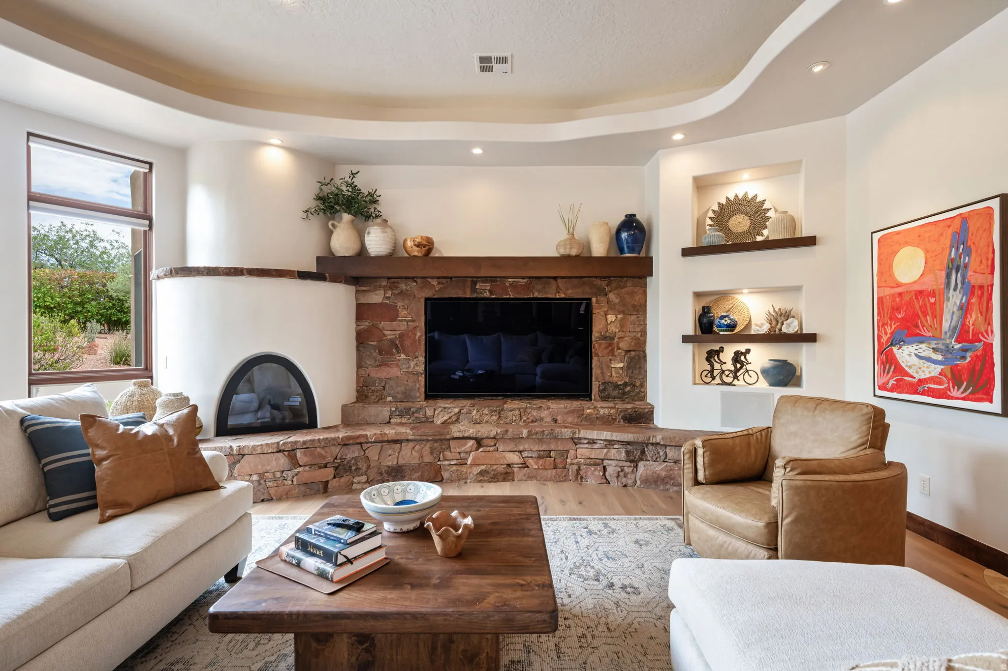 Living area featuring a stone and stucco fireplace with a built-in firebox, a solid wood mantel, and integrated media space