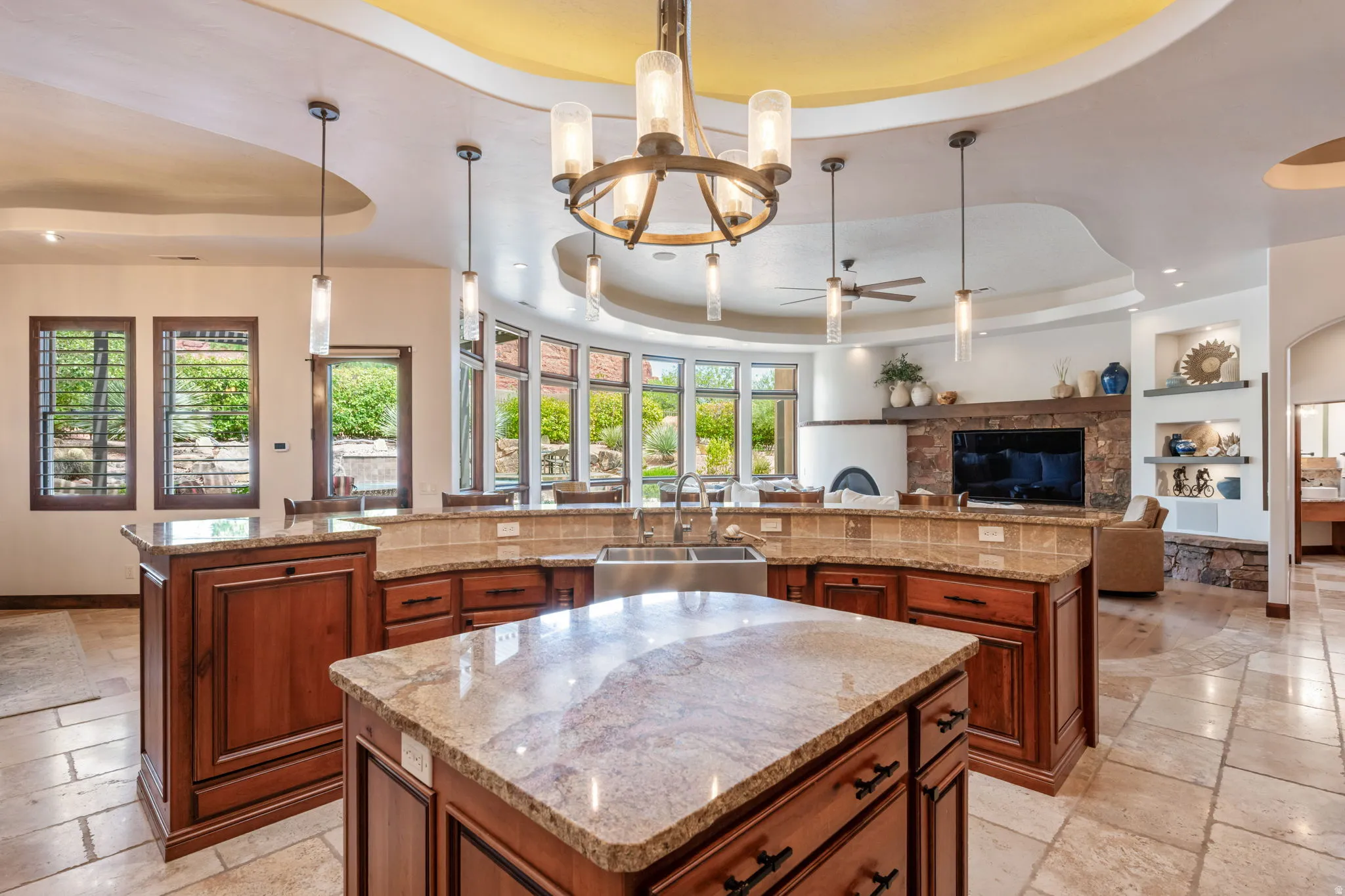 Open-concept kitchen featuring a central island with a stone countertop, rich wood cabinetry, and a double basin sink