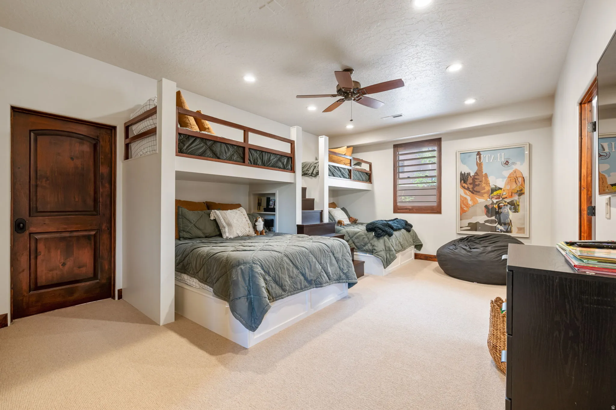 Built-in bunk beds with integrated storage, recessed lighting, ceiling fan, wood-finish door, and carpeted flooring