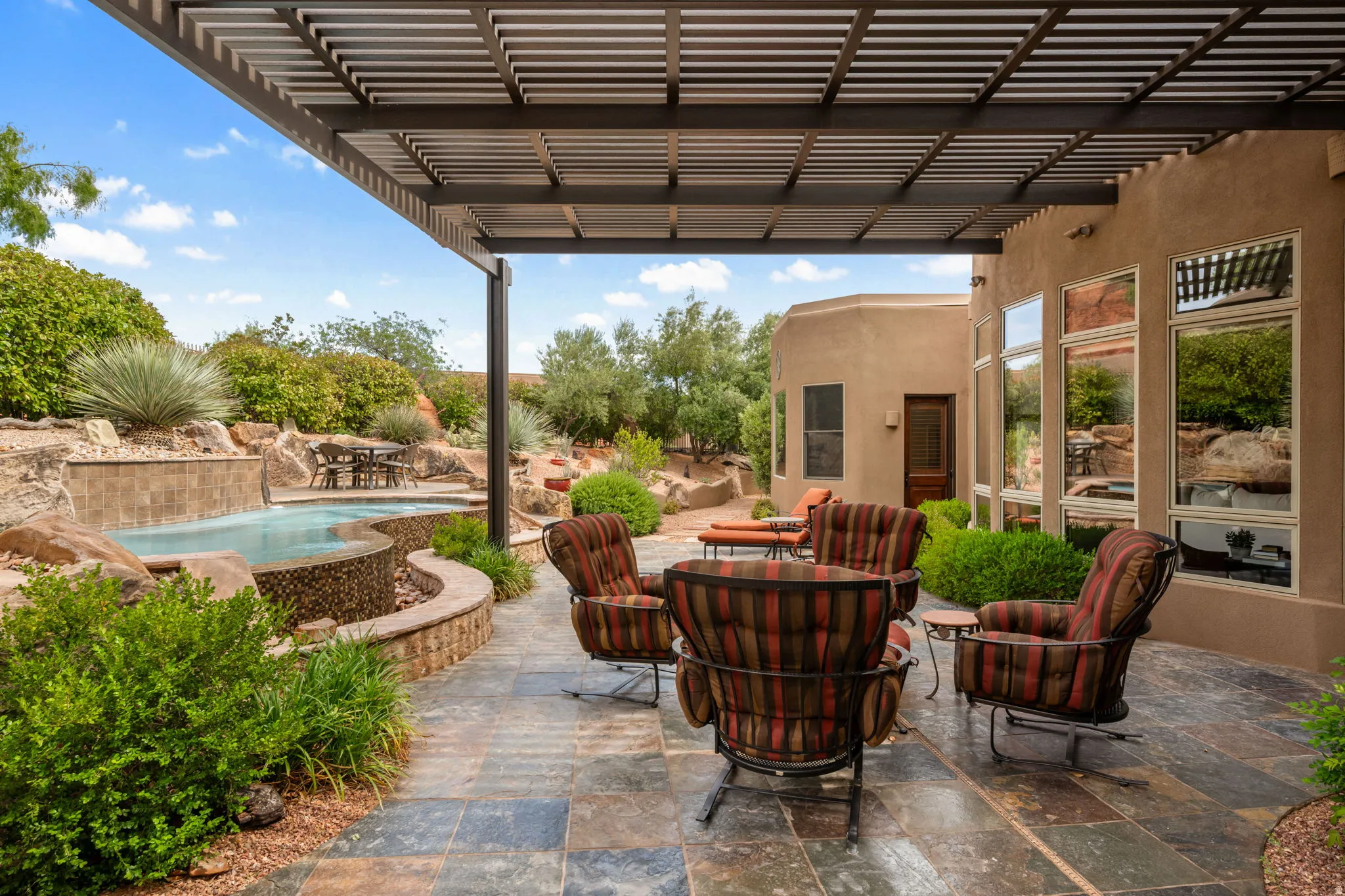 Expansive patio featuring multi-toned flagstone flooring under a louvered pergola