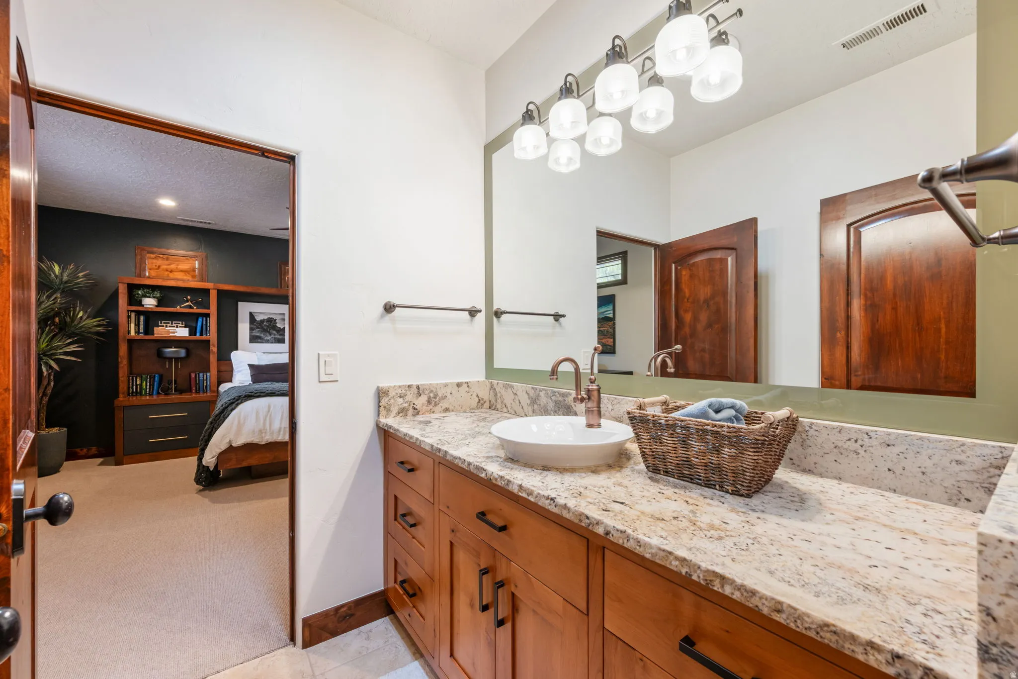 Bathroom vanity featuring a vessel sink, a bronze-finish faucet, and a stone countertop