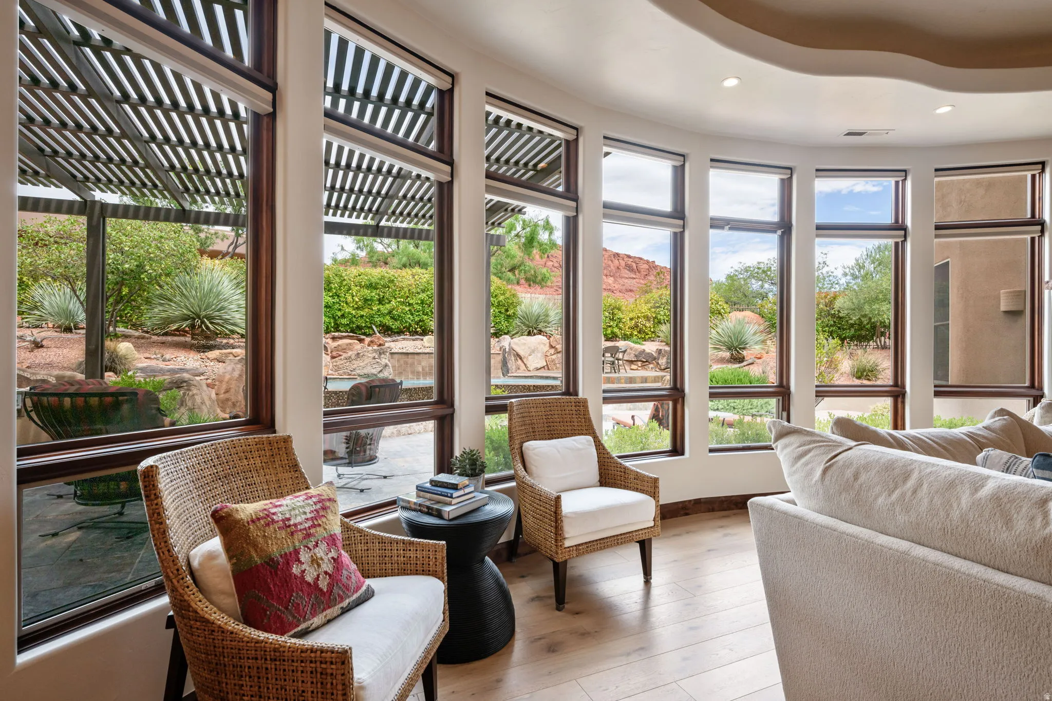 Curved window wall with multiple large windows, wood-finish flooring, a curved ceiling soffit with recessed lighting, and integrated roller shades