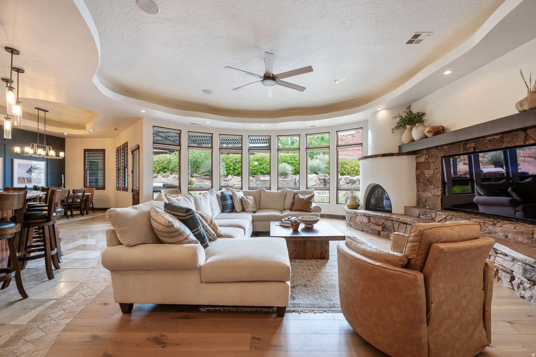 Open-concept living area with a kiva fireplace, stone surround, and wood-finish flooring