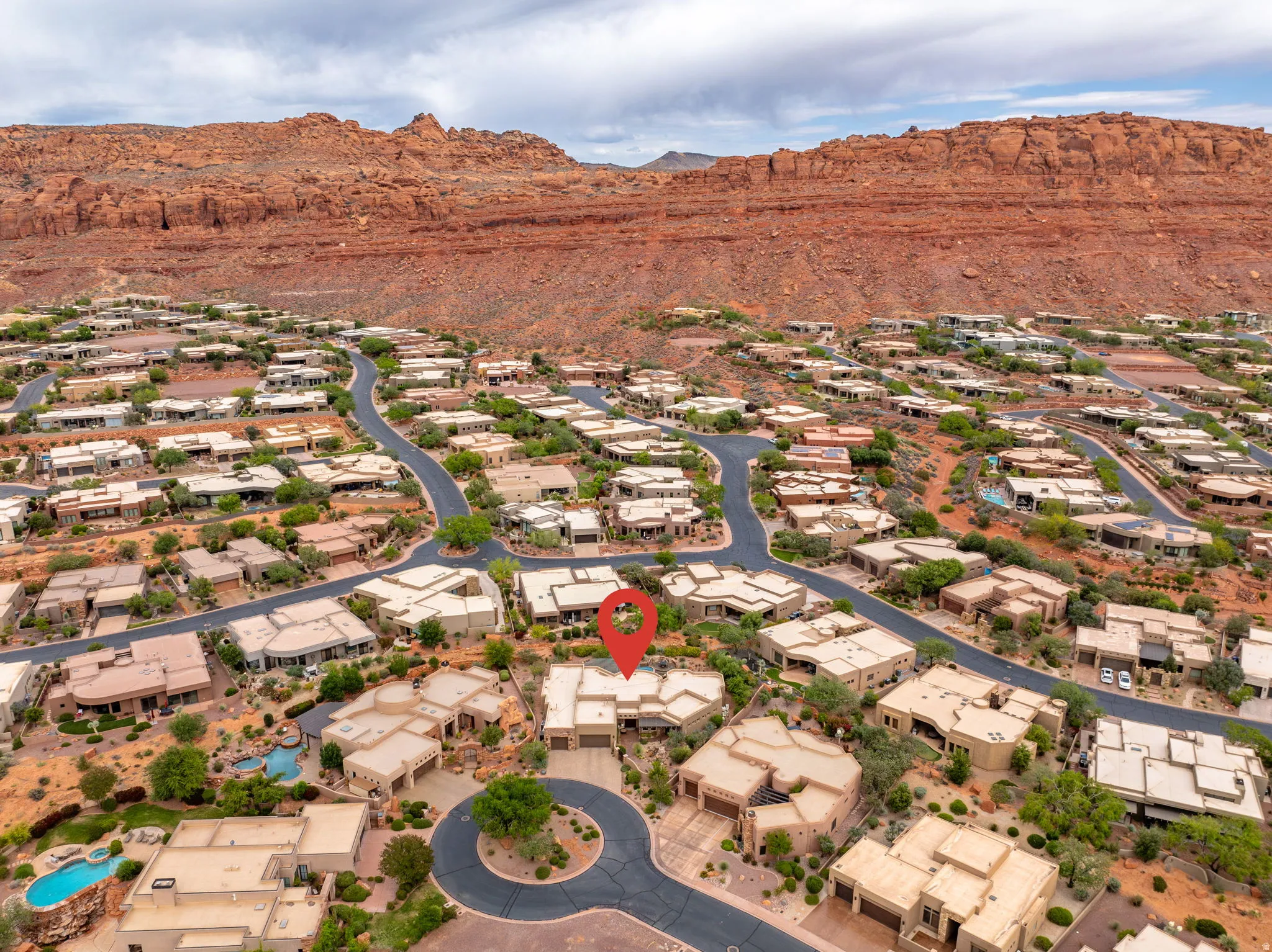 Aerial perspective showcasing a residential community nestled against a backdrop of red rock formations