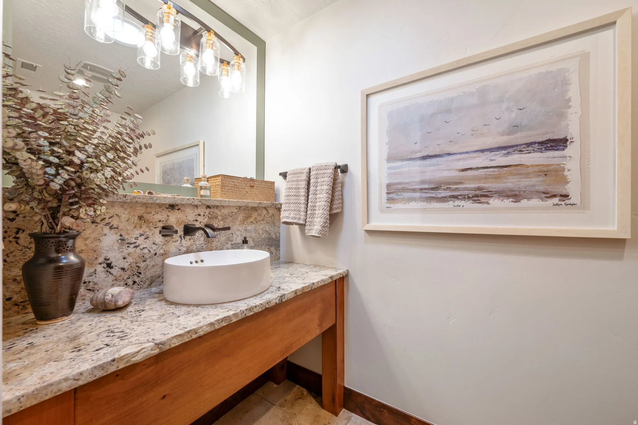 Bathroom vanity featuring a vessel sink, wall-mounted faucet, and a granite countertop with an integrated backsplash