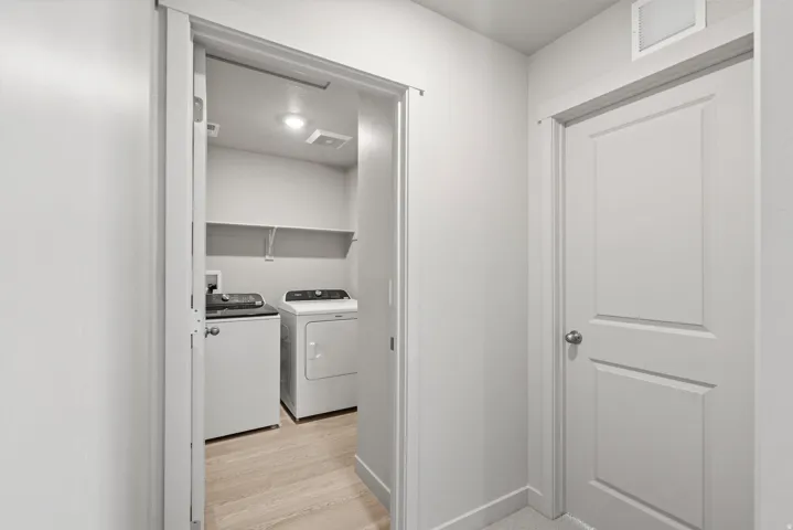 Dedicated laundry area featuring wood-finish flooring, built-in shelving, and recessed lighting