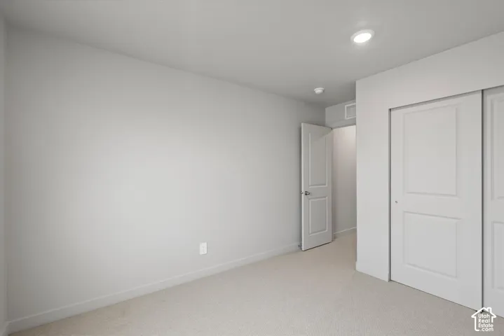 Neutral-toned room featuring light carpet, white baseboards, a white interior door, and two white sliding closet doors