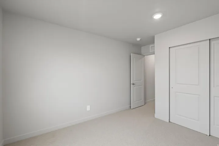 Neutral-toned room featuring light carpet, white baseboards, a white interior door, and two white sliding closet doors