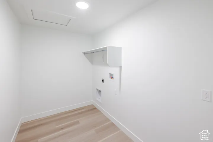 Recessed ceiling lighting, wood-finish flooring, wall-mounted shelving, electrical outlet, and utility hookups