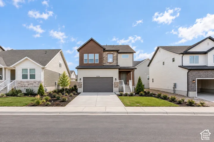Two-story residence featuring a stone and siding exterior, an attached garage, and a concrete driveway