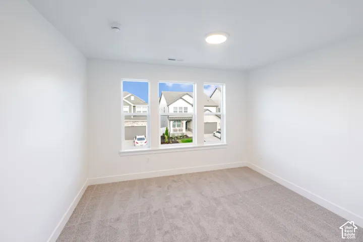 Carpeted room featuring three individual windows and a flush-mount ceiling light