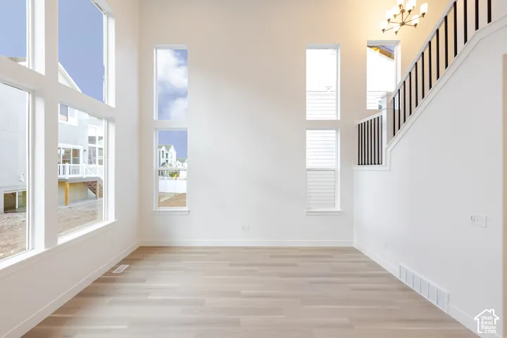 High ceilings with extensive window arrangement, wood-finish flooring, and a staircase featuring black metal balusters and a white handrail