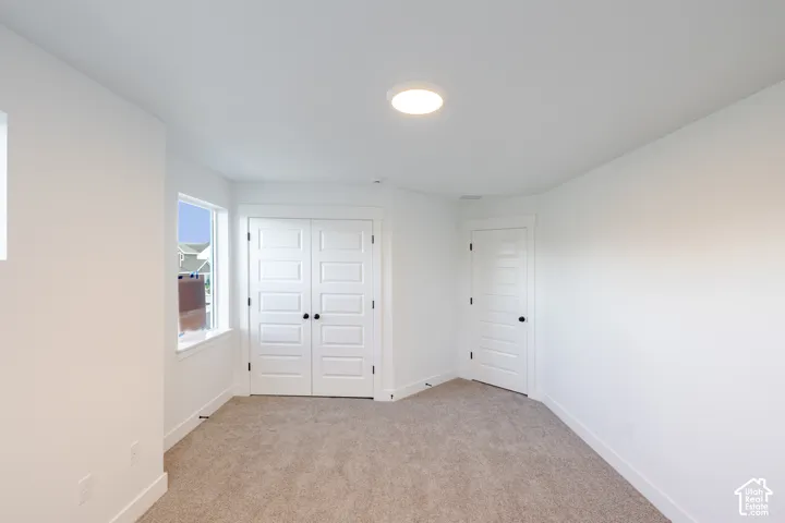 Neutral-toned carpet flooring, a flush-mount ceiling light fixture, and white painted walls