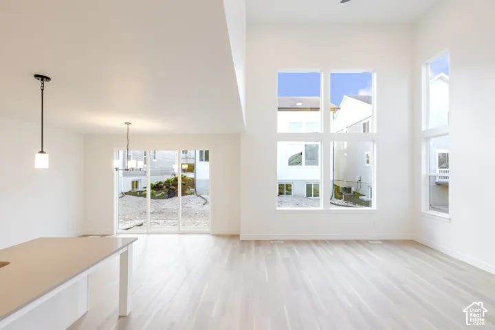 High ceilings with an open-concept layout, expansive windows, wood-finish flooring, and a sliding glass door