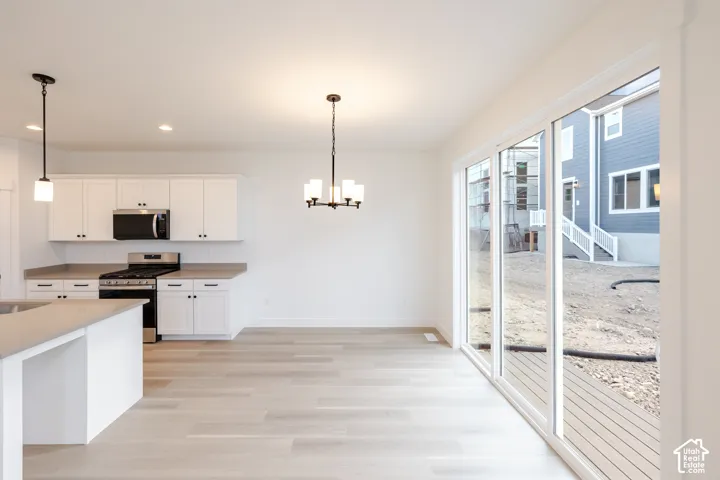 Full kitchen with white cabinetry, stainless steel appliances, and light-toned countertops